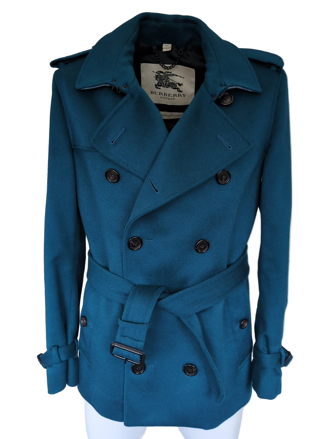 Blue coat on a white surface with a visible brand label.